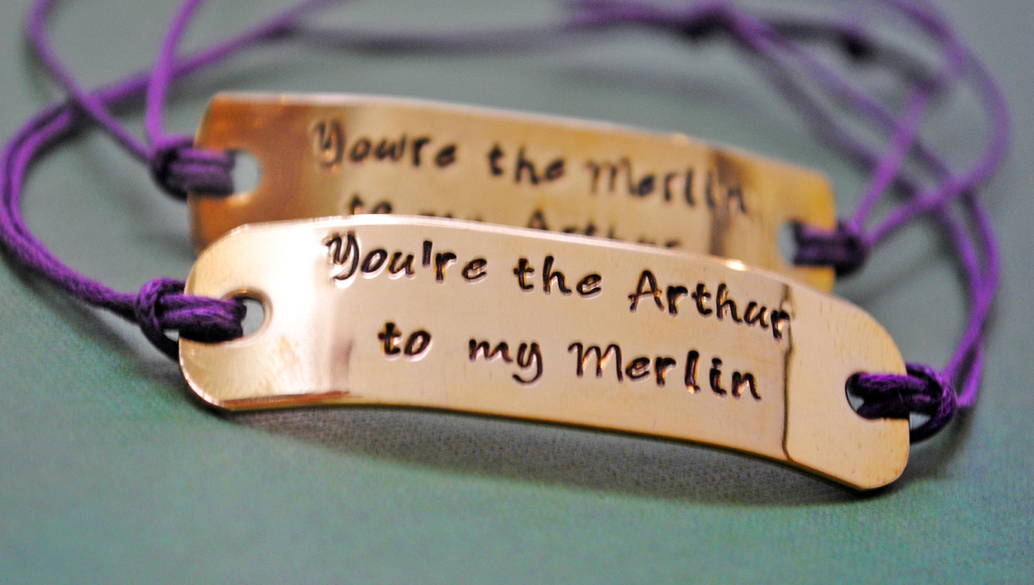 Du bist der Merlin für meinen Arthur, du bist der Arthur für meinen Merlin. Handgestempelte Messing ID Tags, aufgefädelt auf violetter Kordel mit Schiebeknotenverschluss.