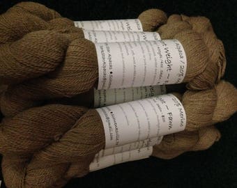 Könnte beinhalten: Knäuel braunes Alpaka-Garn mit Etiketten mit der Aufschrift "Alpaca/20% Merinowolle - Fawn" und "Sportgewicht - 425 Yards/100g Knäuel - 25 €".