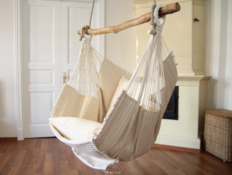 Peut inclure: Un fauteuil hamac ray&eacute; blanc et beige avec un coussin blanc. Le hamac est suspendu &agrave; une poutre en bois.
