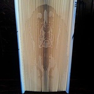 May include: A book folded into the shape of a dog's head. The book is white with blue edges and the dog's head is made of folded pages.