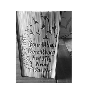 Może przedstawiać: Książka z trójwymiarową papierową grafiką przedstawiającą ptaki odlatujące z tekstem "Your Wings Were Ready But My Heart Was Not".
