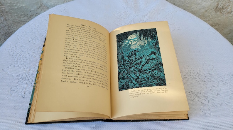 May include: An open book with a black and white illustration of a jungle scene. The text on the page reads "Black Magic".