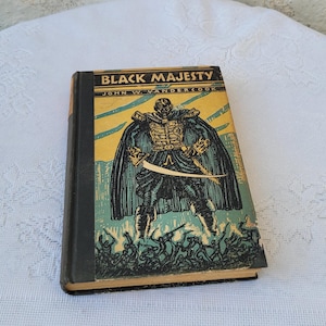 May include: A vintage hardback book titled "Black Majesty" by John W. Vandercook. The cover features a black and white illustration of a man in a cape and holding a sword.