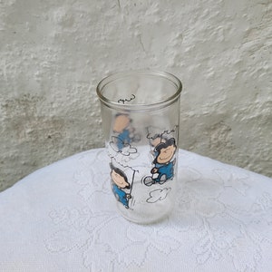 May include: A clear glass with a Peanuts cartoon design featuring Snoopy and Woodstock. The glass has a white background with blue and black cartoon characters.