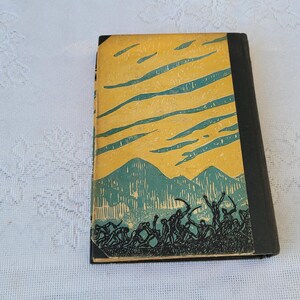 May include: A vintage hardback book with a yellow cover and a black spine. The cover features a green and blue illustration of a mountain range with a sky filled with clouds.