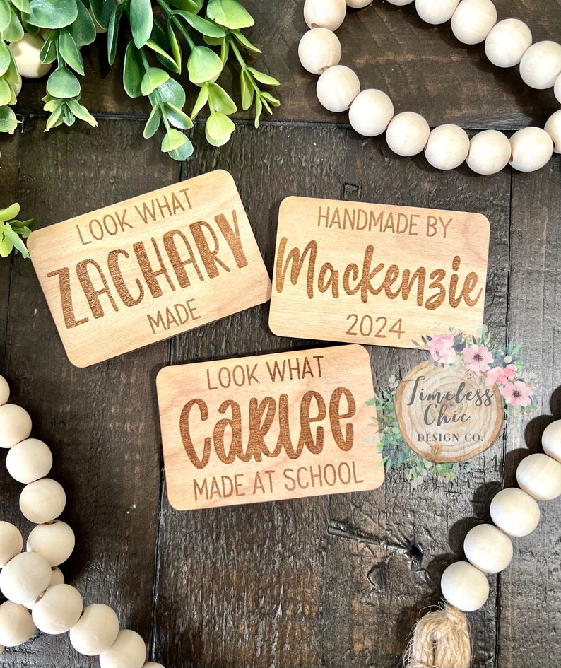 May include: Three wooden signs with personalized text. The first sign says "Look What Zachary Made". The second sign says "Handmade By Mackenzie 2024". The third sign says "Look What Carlee Made At School".