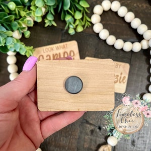 May include: A wooden sign with a round magnet on the front. The sign is blank and ready to be personalized. The sign is made of natural wood and has a rustic look.