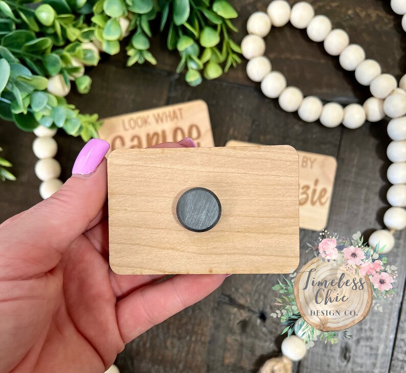 May include: A wooden sign with a round magnet on the front. The sign is blank and ready to be personalized. The sign is made of natural wood and has a rustic look.
