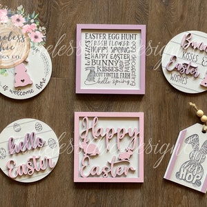 May include: A set of six Easter-themed wooden signs with pink and white paint. The signs feature various Easter-related phrases and images, including bunnies, eggs, and the words "Happy Easter", "Bunny Kisses & Easter Wishes", and "Hello Easter".