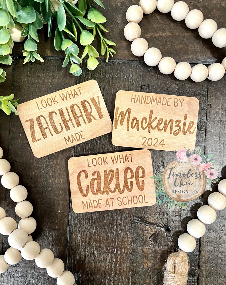 May include: Three wooden signs with engraved text. The first sign says "Look What Zachary Made". The second sign says "Handmade By Mackenzie 2024". The third sign says "Look What Carlee Made At School".