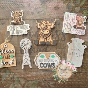 May include: A set of eight wooden signs with various Highland Cow designs and sayings. The signs feature phrases like "Home is where the herd is", "Life is better with fluffy cows", and "Bless our herd".