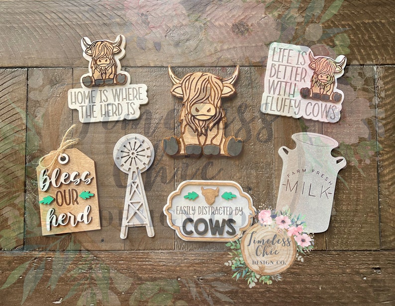 May include: A set of eight wooden signs with various Highland Cow designs and sayings. The signs feature phrases like "Home is where the herd is", "Life is better with fluffy cows", and "Bless our herd".