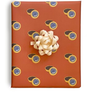 May include: A brown gift wrap with a repeating pattern of yellow caviar tins with a blue fish and the word 'Caviar' printed on them. A white bow is in the center of the wrapping paper.