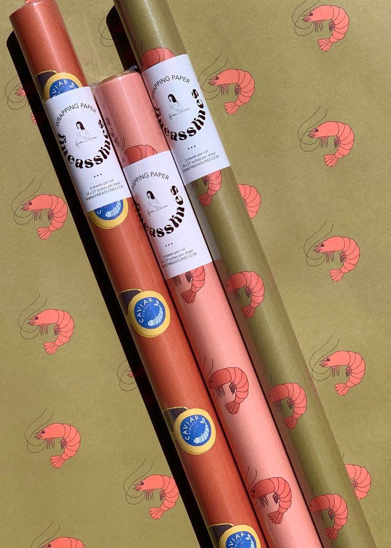 May include: Three rolls of wrapping paper with a shrimp pattern. The rolls are in different colors: green, pink, and orange. The wrapping paper is labeled 'Fine Asslines' and includes the website address 'www.fineasslines.com'. Each roll has a small sticker with the word 'Caviar' and a shrimp design.