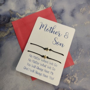 May include: A white card with the text "Mother & Son" and the message "No Matter Where We Go No Matter What We Do You Will Always Have Me And I Will Always Have You!" Two black string bracelets with gold star charms are attached to the card.
