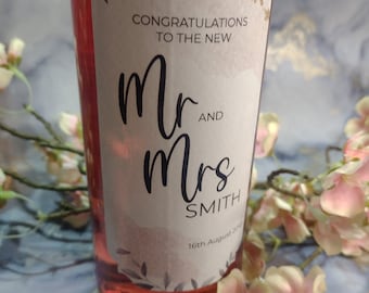 May include: A pink wine bottle with a white label that says "Congratulations to the new Mr. and Mrs. Smith 16th August 2023".