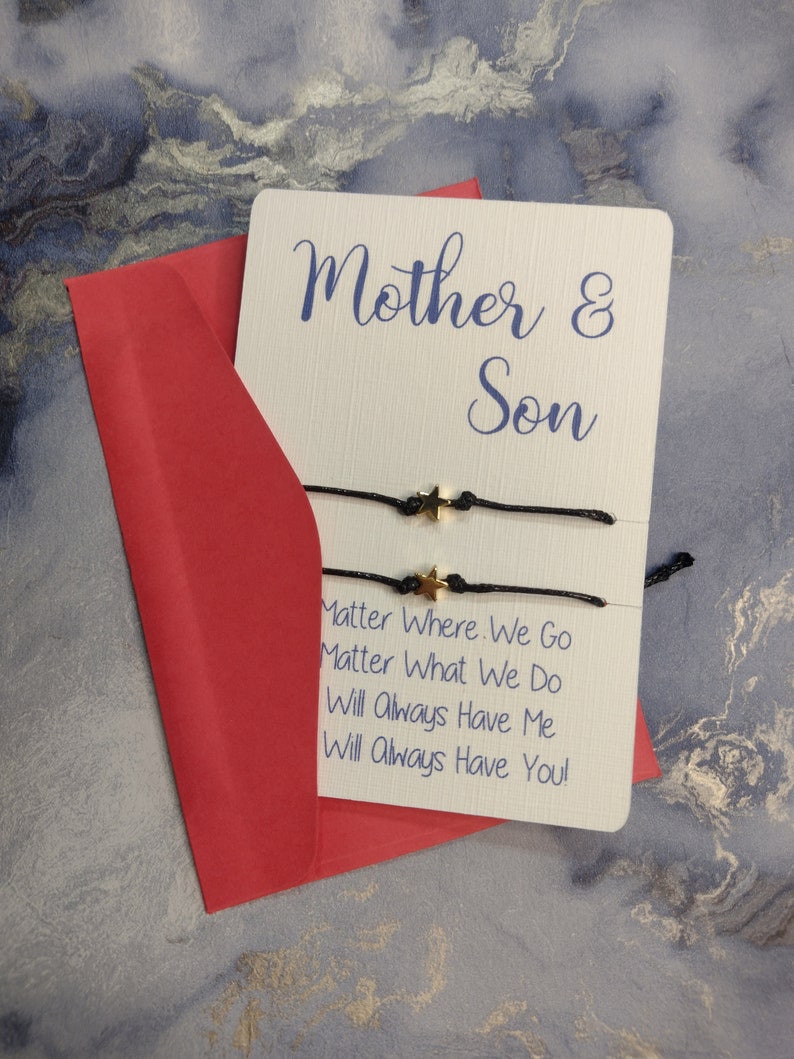 May include: A white card with the text "Mother & Son" and the message "Matter Where We Go Matter What We Do Will Always Have Me Will Always Have You!"  The card is sitting on a red envelope.