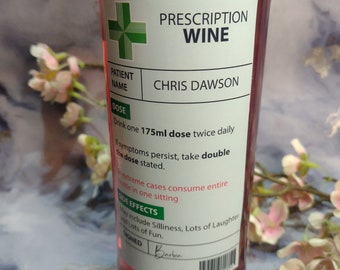 Puede incluir: Una etiqueta verde y blanca en una botella de vino dice "Prescription Wine" con el nombre del paciente "Chris Dawson". La etiqueta incluye instrucciones para tomar una dosis de 175 ml dos veces al día y enumera los efectos secundarios como "Silliness, Lots of Laughter and Lots of Fun."