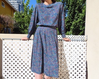 Completo Paisley anni '80, blu e viola, con polsini a maniche lunghe, gonna plissettata sotto il ginocchio e vita elasticizzata. Coordinate: taglia Large - busto 42" / vita 30"