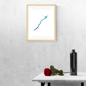 May include: A framed abstract watercolor painting of a blue line on a white background, a single red rose on a white table, and a black bottle on the table.
