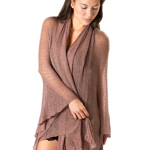 May include: A woman wearing a brown, open-front knit cardigan with a loose, flowing silhouette. The cardigan is made of a lightweight, airy fabric and has a relaxed, casual style.