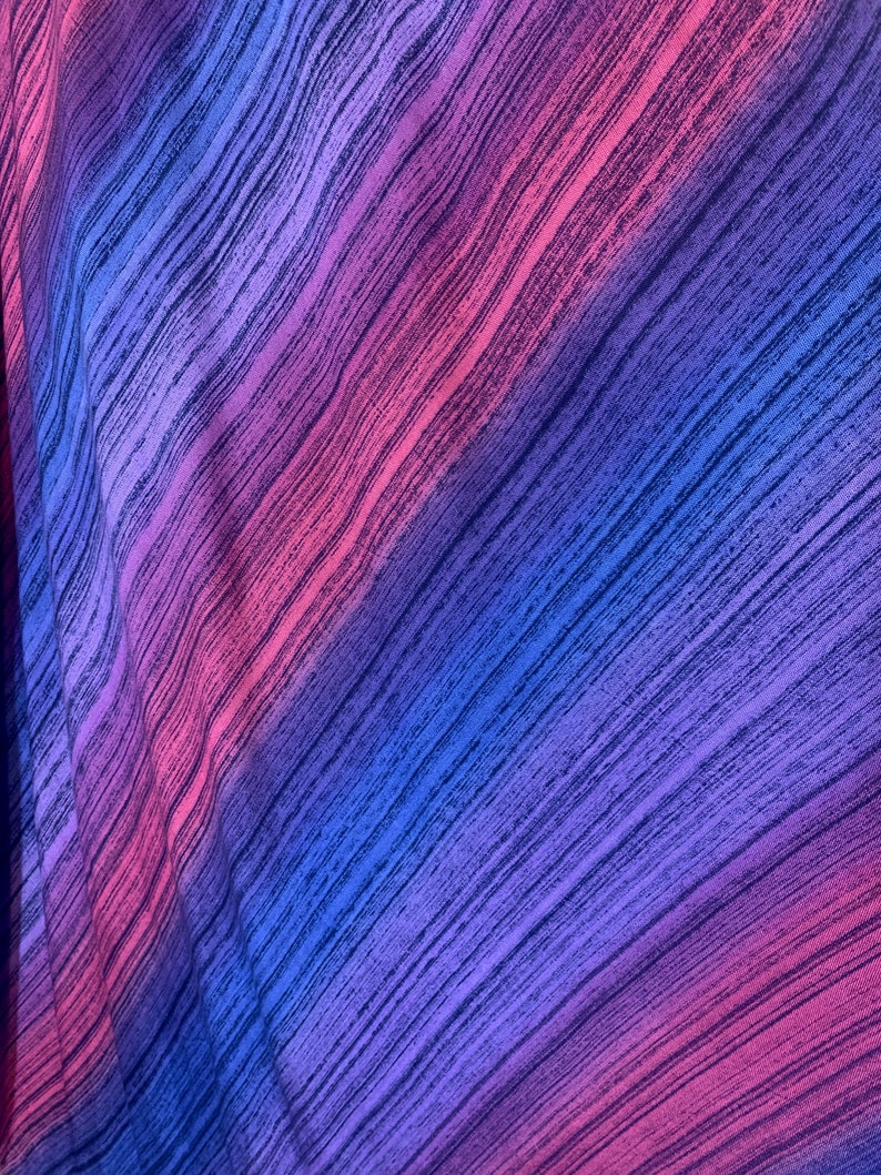 Puede incluir: Primer plano de una tela con un patr&oacute;n de rayas diagonales en tonos azules, morados y rosas.