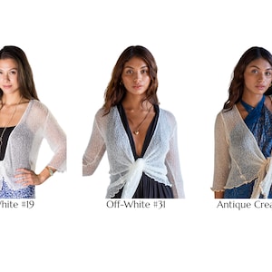 May include: Three cropped shrugs with three-quarter sleeves and a tie-front closure. The shrugs are shown in white labeled #19, off-white labeled #31, and antique cream labeled #36. Each garment features a lightweight, semi-sheer knit texture.