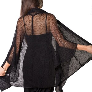 May include: Black sheer knit cardigan with a loose, flowing silhouette. The cardigan is made of a lightweight, breathable fabric and has a relaxed fit.