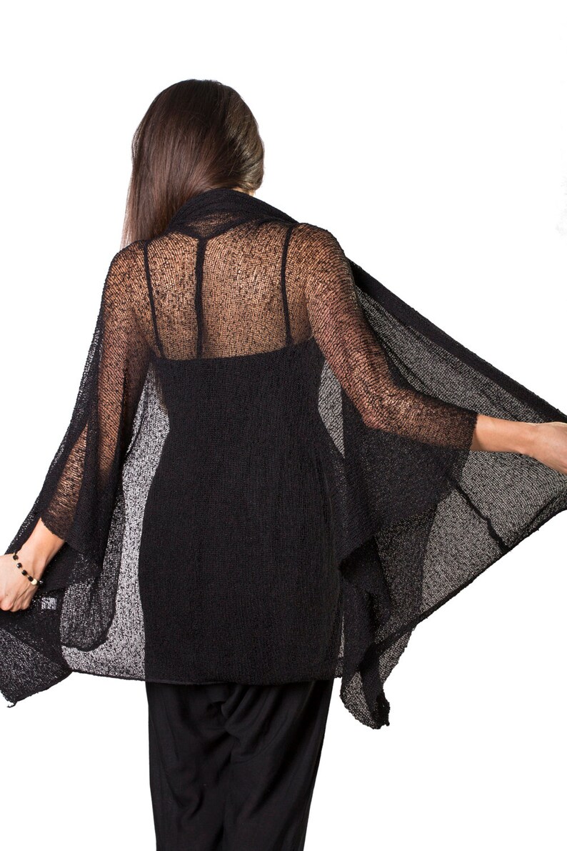 May include: Black sheer knit cardigan with a loose, flowing silhouette. The cardigan is made of a lightweight, breathable fabric and has a relaxed fit.