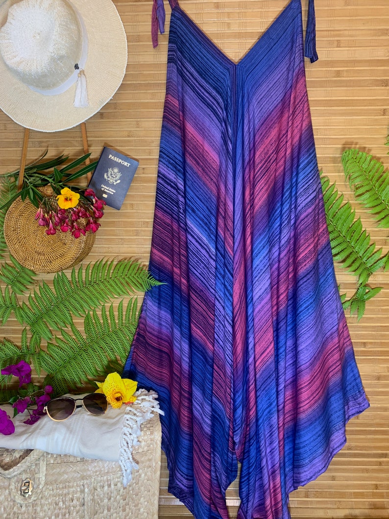 Puede incluir: Un mono de rayas de color morado, azul y rosa con tirantes finos. El mono tiene cuello en V y un corte holgado y fluido.