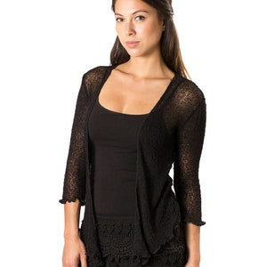 May include: A black open-front cardigan with three-quarter length sleeves and a textured knit pattern, worn over a black tank top and black shorts featuring a decorative scalloped crochet lace hemline with intricate circular patterns.