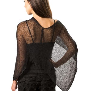 May include: A black sheer knit top with wide, flowing sleeves and a loose, textured weave, paired with black crochet shorts featuring a scalloped hemline and intricate circular patterns throughout the fabric, creating a layered dark ensemble.