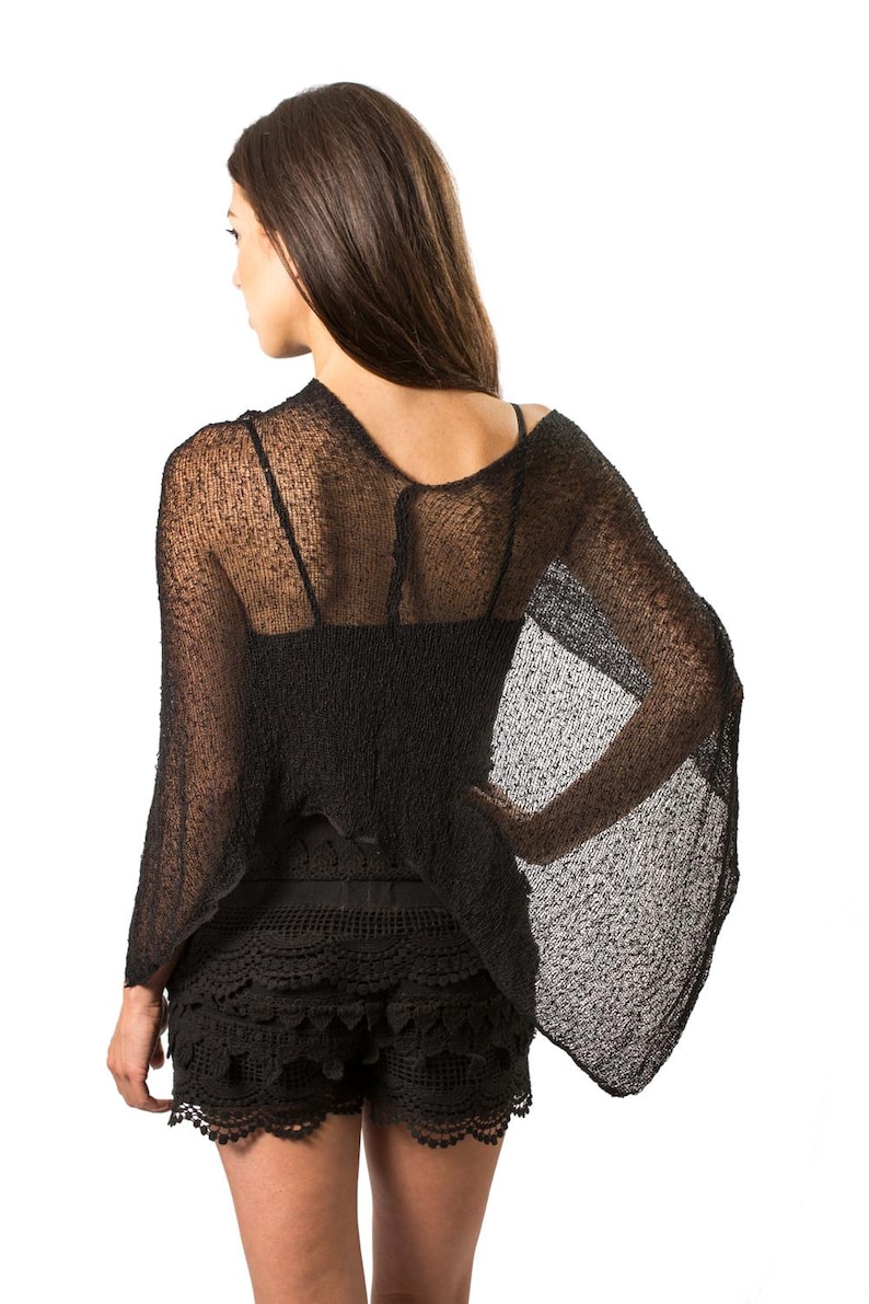 May include: A black sheer knit top with wide, flowing sleeves and a loose, textured weave, paired with black crochet shorts featuring a scalloped hemline and intricate circular patterns throughout the fabric, creating a layered dark ensemble.