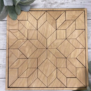 May include: A wooden geometric design puzzle with a light brown finish. The puzzle is made up of many small pieces that fit together to create a larger design.