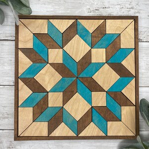 May include: A geometric wooden wall art piece with a teal and brown colour scheme. The design is made up of squares and triangles that create a 3D effect.
