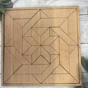 May include: A square wooden plaque with an etched geometric design. The design is made up of black lines that create a series of triangles and squares.