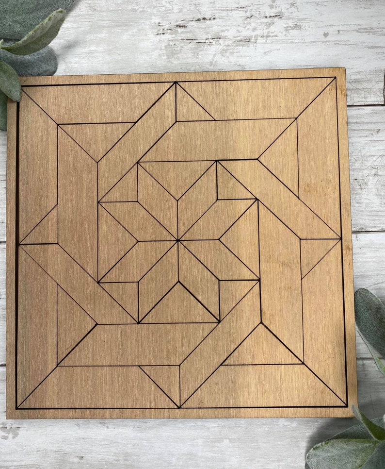 May include: A square wooden plaque with an etched geometric design. The design is made up of black lines that create a series of triangles and squares.