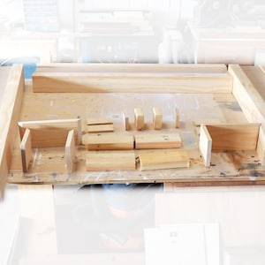 May include: A set of unfinished wooden pieces for building a frame. The pieces are arranged on a workbench, ready to be assembled.