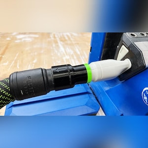May include: A black and green dust extraction hose with a black and white Festool label connected to a white dust extraction port on a blue power tool.