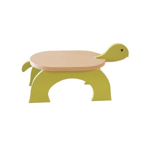 May include: A green wooden turtle-shaped stool with a light brown top. The stool is designed for children and has a playful, whimsical design.