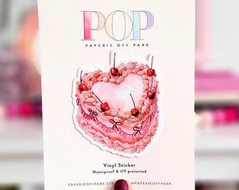 May include: A pink heart-shaped cake sticker with cherries and bows. The sticker is on a white card with the text "POP" and "PAPERIE OFF PARK". The sticker is waterproof and UV protected.