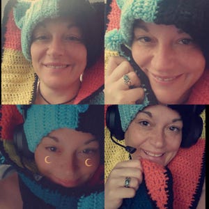 May include: A woman is wearing a colorful crocheted hat and scarf. The hat has a blue, black, and white pattern, and the scarf has a yellow, red, and black pattern. The woman is smiling and looking at the camera.