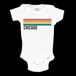 May include: White baby onesie with a retro-style striped design in red, orange, yellow, green, and brown. The text "CHICAGO" is printed in black below the stripes.