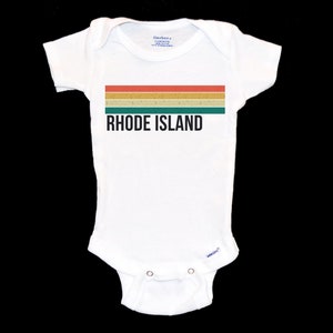 May include: White baby onesie featuring a retro-style striped design in red, orange, yellow, and green. The text "RHODE ISLAND" is printed in black below the stripes.