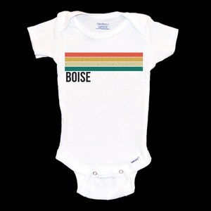 May include: White baby onesie with a retro-style striped design in orange, yellow, green, and brown. The onesie has the word "BOISE" printed in black.
