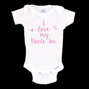 Puede incluir: Un body blanco para beb&eacute; con texto rosa que dice "I love my Uncle Joe" con una flecha apuntando a la izquierda y un remolino a la derecha.