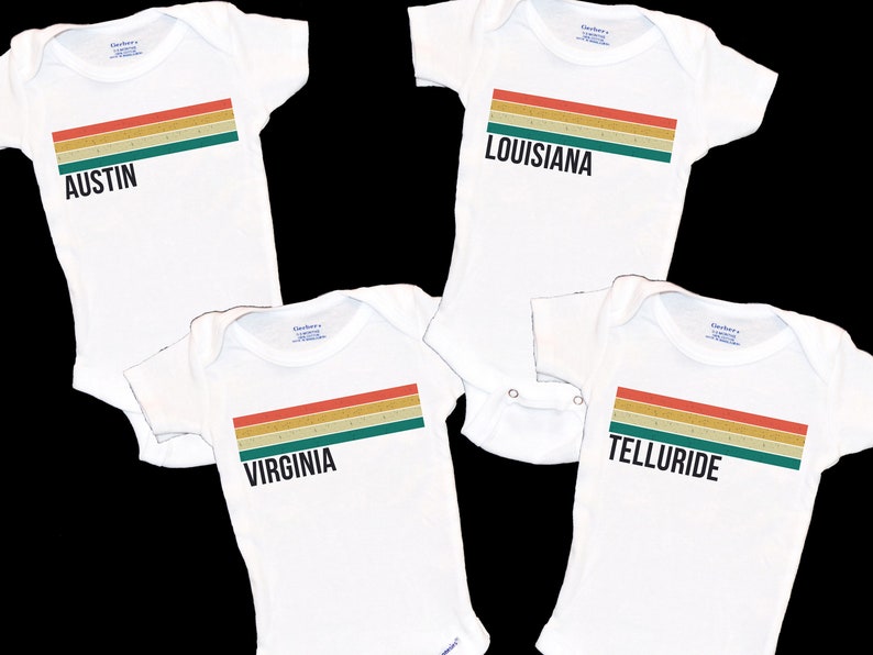 May include: Four white baby onesies with a colorful striped design and the words "Austin", "Louisiana", "Virginia", and "Telluride" printed on them.