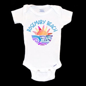May include: White baby onesie with a colorful graphic of a sun setting over waves and the text "Rosemary Beach" in blue.