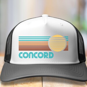 May include: A white and black trucker hat with a retro-style graphic of a sun setting over a city skyline. The text "CONCORD" is printed in blue on the front of the hat.