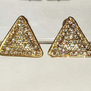 May include: A pair of gold triangle earrings with clear rhinestones.